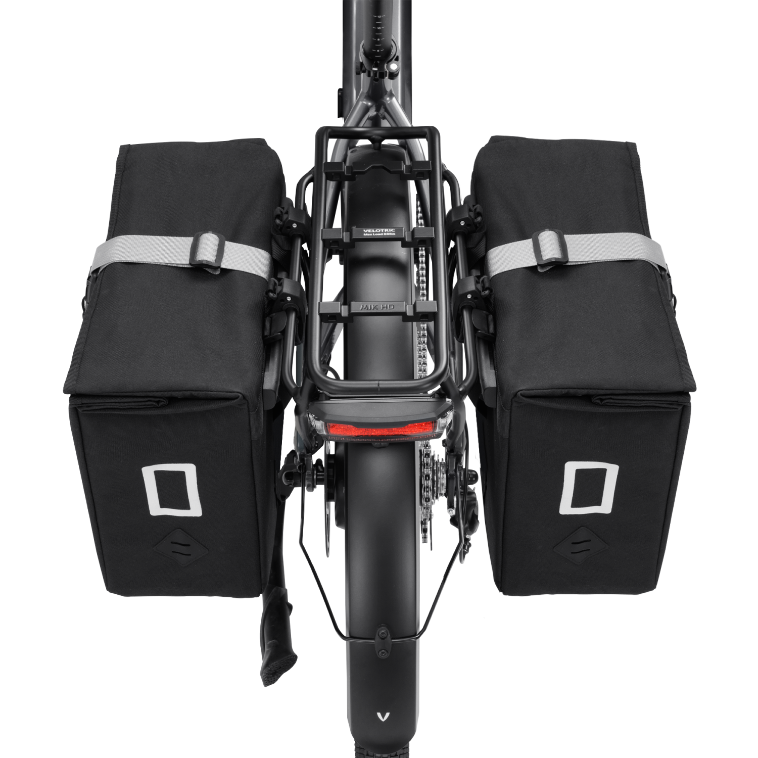 Dual Velotric black pannier bags on bicycle rear rack for added storage.