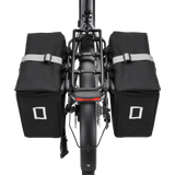 Dual Velotric black pannier bags on bicycle rear rack for added storage.